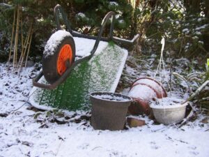 wheelbarrow and gardening tools covered in snow