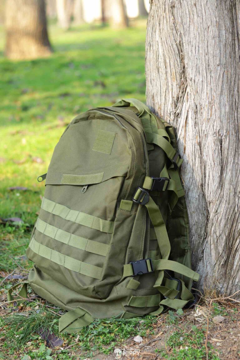 green MOLLE backpack next to tree