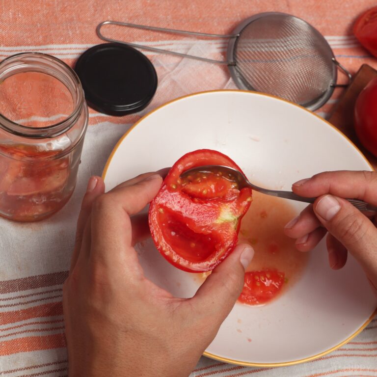 scooping tomato flesh with a teaspoon
