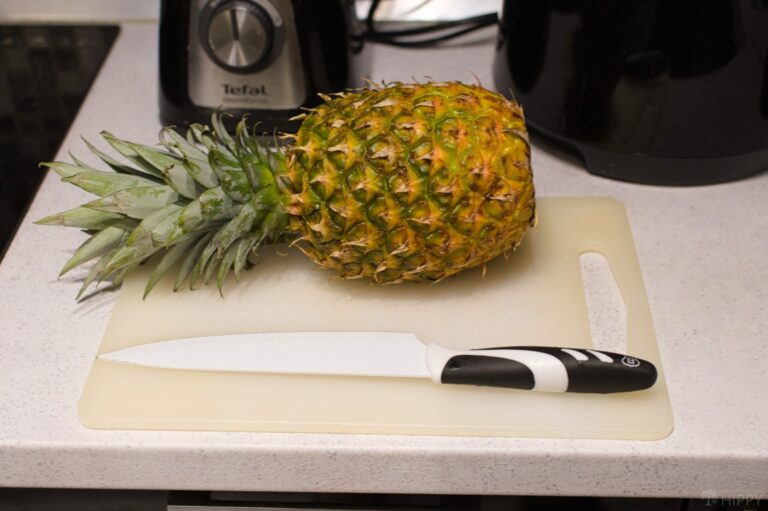 a whole pineapple next to a large knife