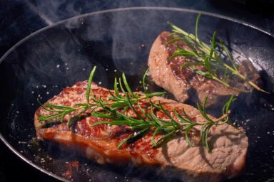 cooking steak with rosemary in a non stick pan